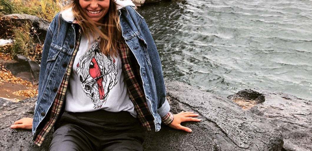 laughing in layers, wearing a graphic tee, a flannel, and a jean jacket