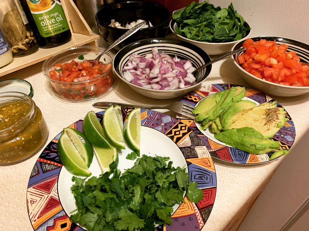 fresh veggie toppings for double deck vegan cauliflower tacos. Tomatoes, red onions, avocado, spinach, cilantro, limes, salsa