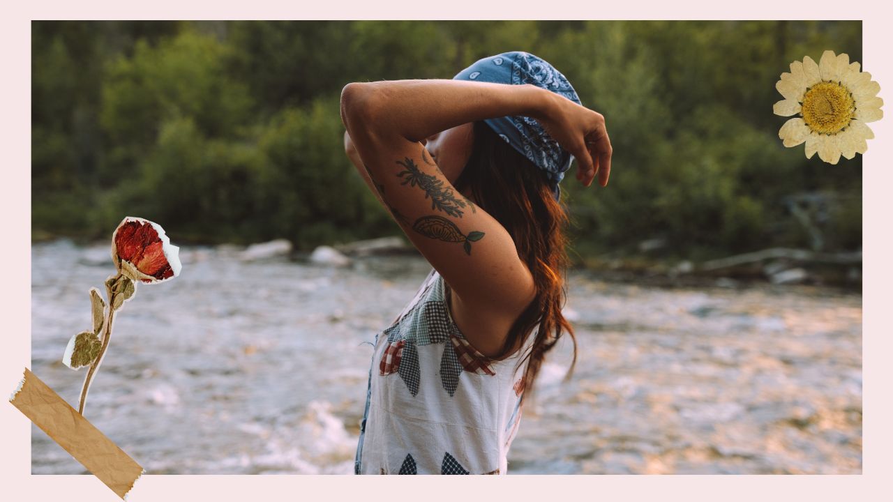 woman wearing a dress and a bandana, standing in front of river with arms raised, scrapboook-style flowers, one rose with a piece of tape on the left and one single daisy flower on the right